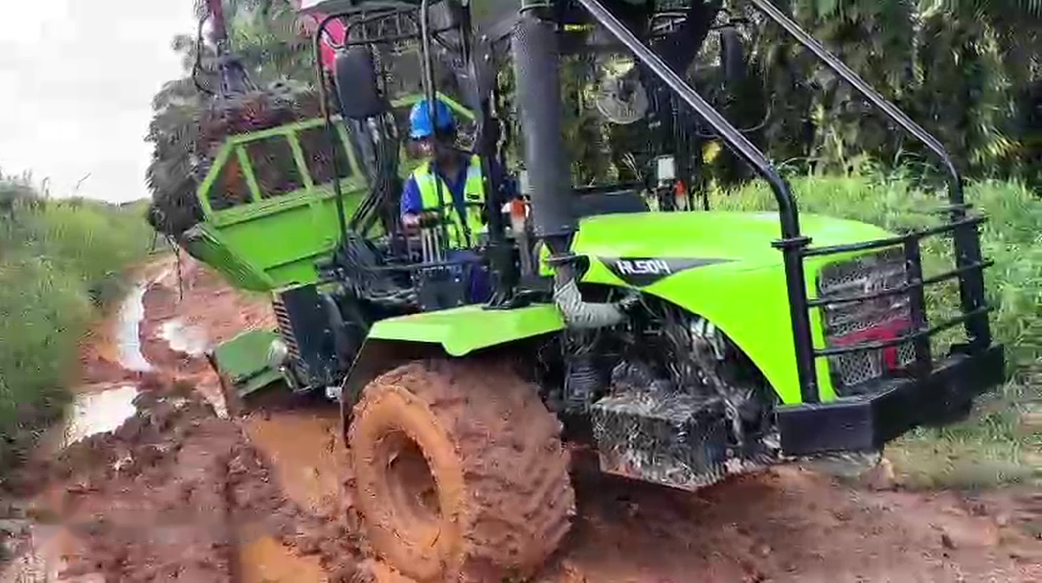 HL Series (Huili) articulated tractor on a muddy oil palm estate track